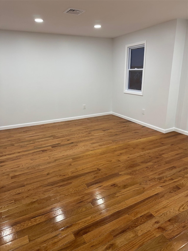 unfurnished room with baseboards, visible vents, dark wood-type flooring, and recessed lighting