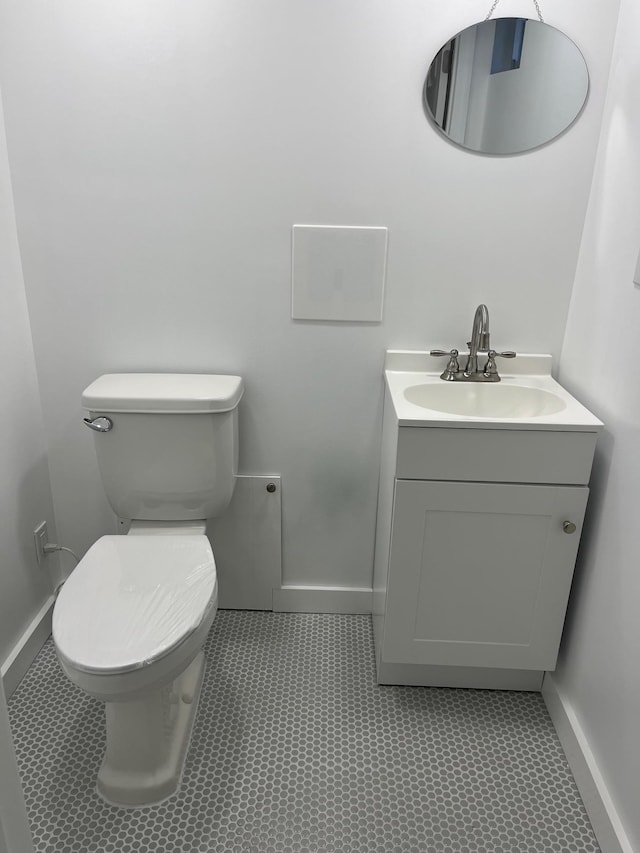 half bath featuring toilet, vanity, and baseboards