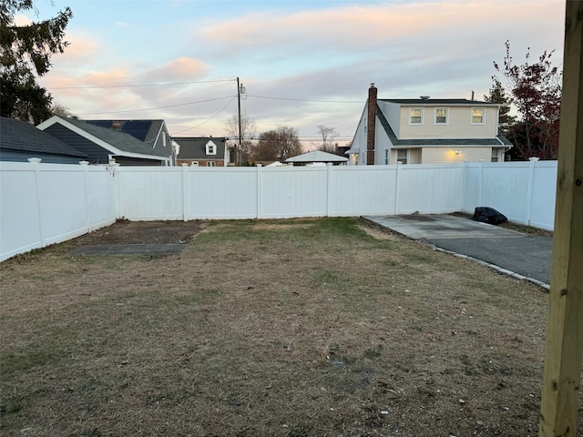 yard at dusk featuring a fenced backyard and a patio