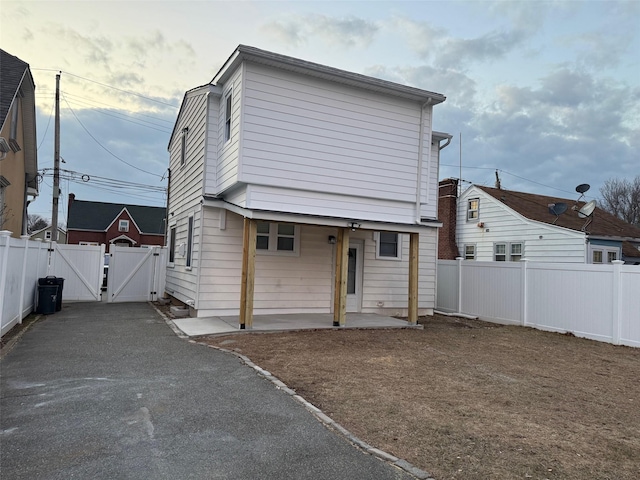 back of property with a patio area, fence, and a gate