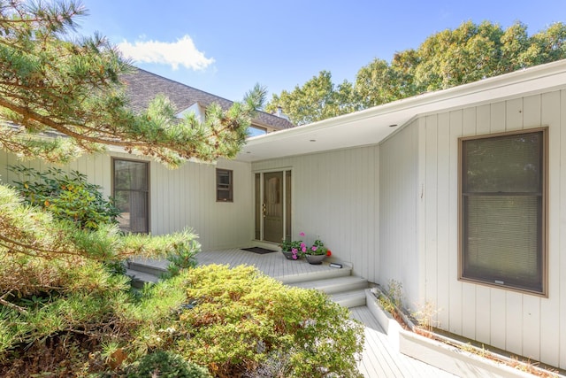 doorway to property with roof with shingles