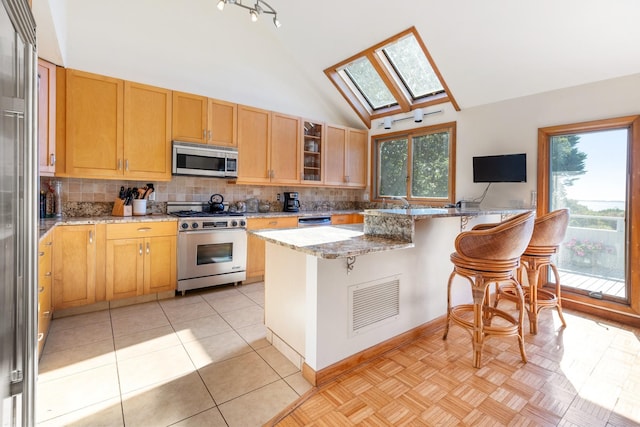 29 Kenwood Rd, Southampton, NY 11968 - kitchen featuring visible vents, decorative backsplash, light stone counters, stainless steel appliances, and a kitchen bar