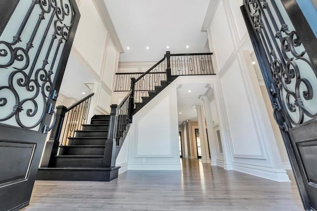 foyer with a high ceiling, stairway, a decorative wall, and wood finished floors