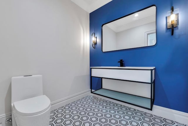 bathroom with ornamental molding, vanity, toilet, and baseboards