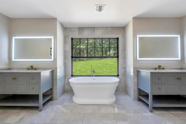 full bathroom with a sink, visible vents, two vanities, and tile walls