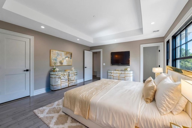 bedroom with baseboards, visible vents, a raised ceiling, wood finished floors, and recessed lighting