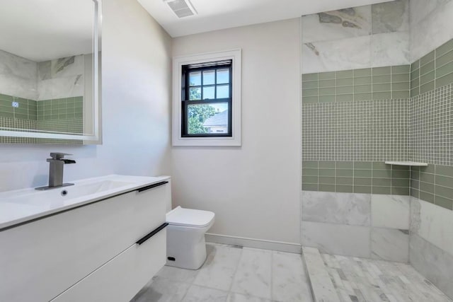 bathroom featuring baseboards, visible vents, tiled shower, toilet, and vanity