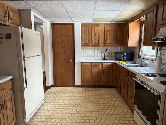 kitchen with white appliances, light countertops, a sink, and brown cabinetry