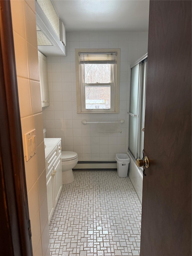 full bathroom with combined bath / shower with glass door, a baseboard radiator, vanity, and tile walls