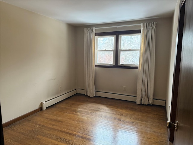 empty room featuring a baseboard radiator, baseboards, and dark wood finished floors