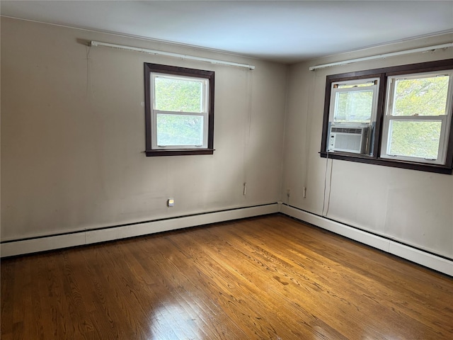 spare room featuring cooling unit, plenty of natural light, and wood finished floors