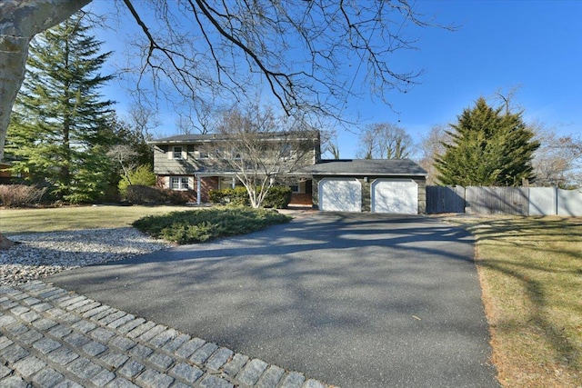 view of front of home featuring aphalt driveway, an attached garage, and fence