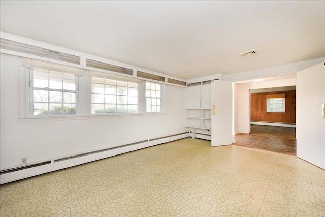 empty room with a baseboard radiator, visible vents, a wealth of natural light, and tile patterned floors