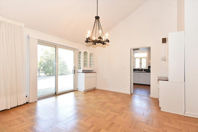 spare room with high vaulted ceiling, visible vents, a notable chandelier, and baseboards