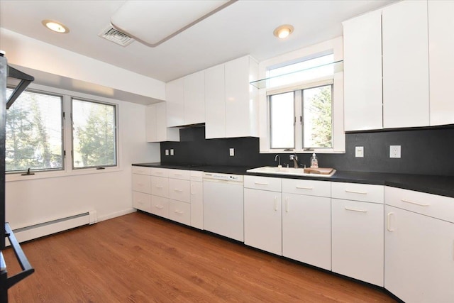 kitchen with dark countertops, visible vents, a baseboard heating unit, white dishwasher, and wood finished floors