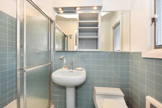 full bathroom with a stall shower, tile walls, and toilet