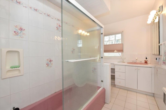 full bath with tile patterned flooring, combined bath / shower with glass door, tile walls, and vanity