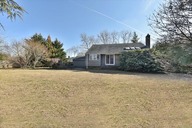 view of front facade with a chimney and a front yard