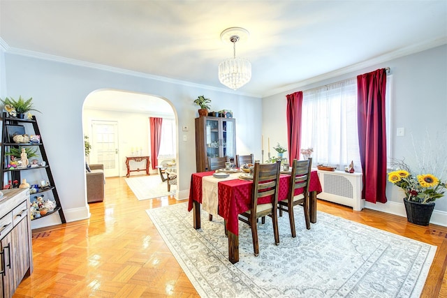 dining space featuring arched walkways, crown molding, baseboards, and an inviting chandelier