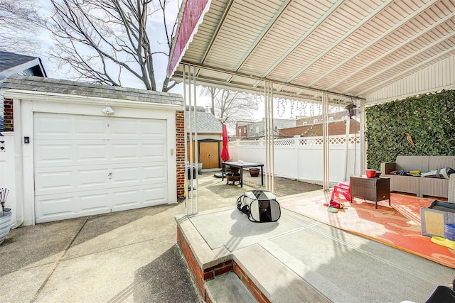 detached garage featuring concrete driveway and fence