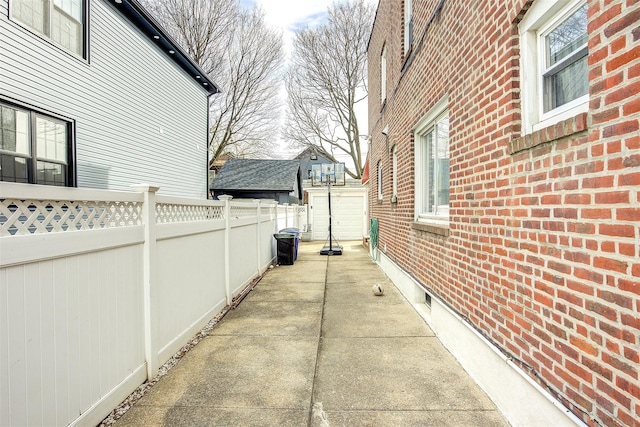 view of side of property featuring a patio area, brick siding, and a fenced backyard