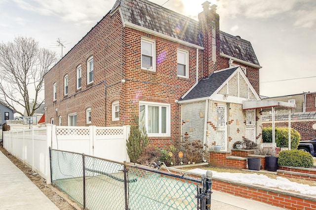 view of front of house featuring brick siding, a fenced front yard, and a chimney