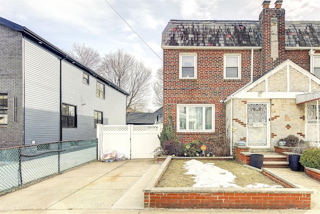 view of front of home featuring brick siding, driveway, a gate, and fence