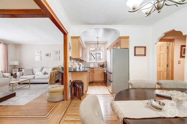 dining space featuring light wood finished floors, a chandelier, arched walkways, and crown molding