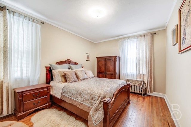 bedroom with ornamental molding, hardwood / wood-style floors, and baseboards