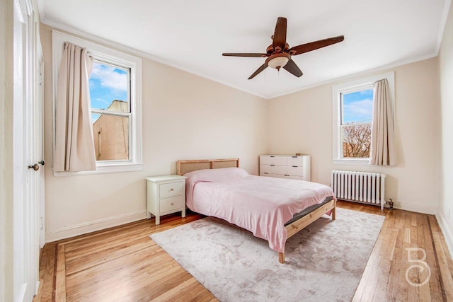 bedroom featuring baseboards, light wood finished floors, and radiator