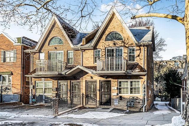 view of front facade featuring brick siding, a fenced front yard, and a balcony