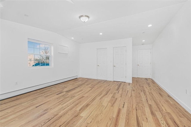 interior space featuring baseboards, lofted ceiling, baseboard heating, light wood-type flooring, and recessed lighting