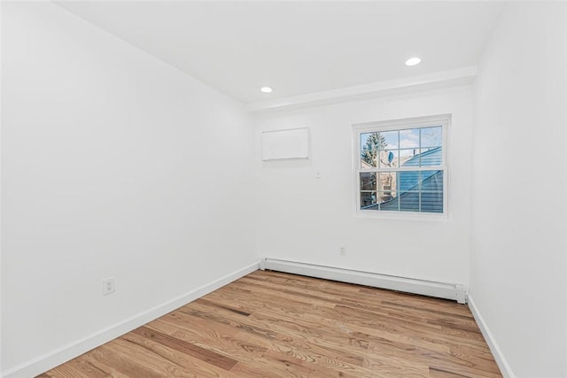 empty room featuring light wood-type flooring, a baseboard radiator, baseboards, and recessed lighting