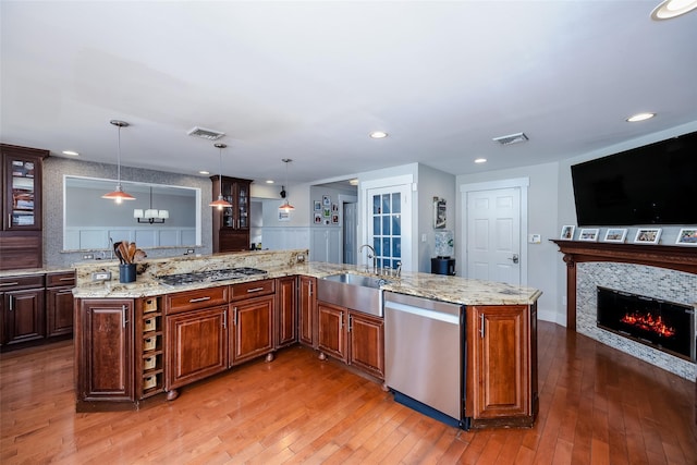 kitchen with decorative light fixtures, stainless steel appliances, a sink, open floor plan, and a large island with sink