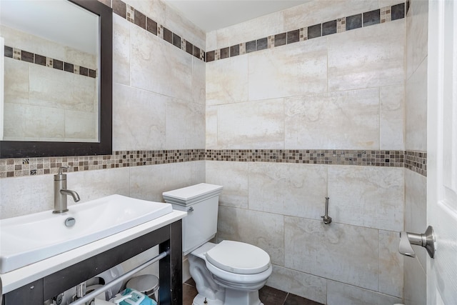 half bathroom with toilet, tile walls, and vanity