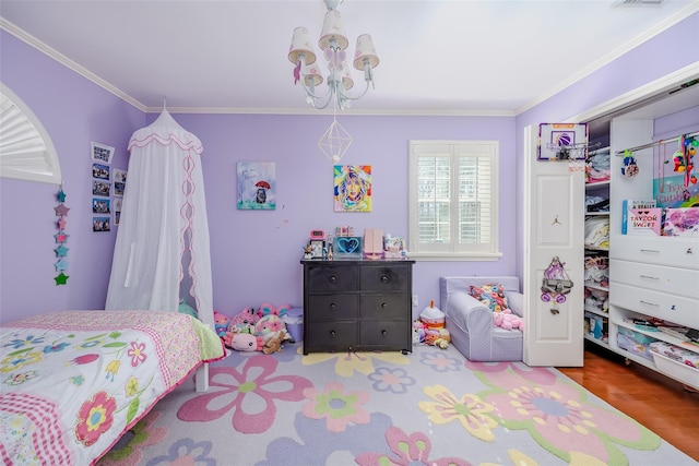 bedroom featuring a closet, ornamental molding, a chandelier, and wood finished floors