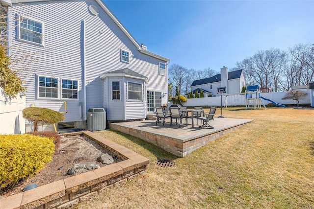 back of property featuring central AC unit, a patio, fence, a yard, and a playground