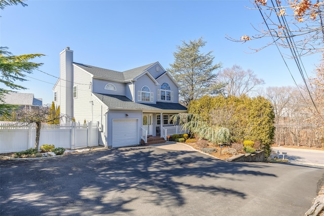 view of front of home featuring a shingled roof, a chimney, aphalt driveway, fence, and a porch