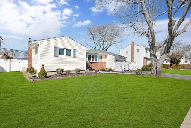 back of house featuring a yard, a gate, fence, a garage, and driveway