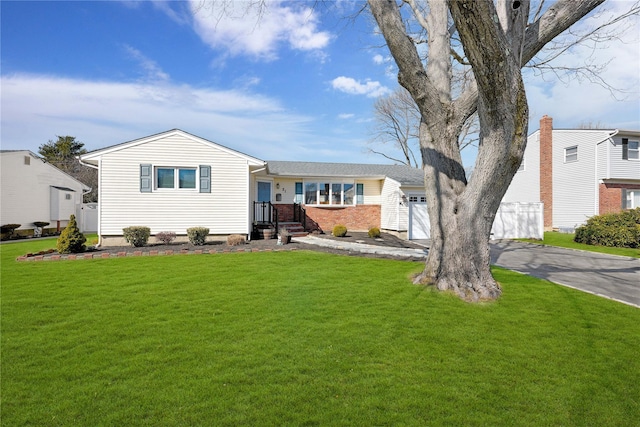 ranch-style home with a garage, brick siding, fence, driveway, and a front yard