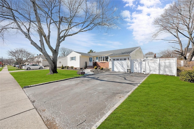 view of front of home with driveway, an attached garage, fence, a front yard, and brick siding