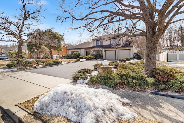 view of front facade featuring a chimney, stucco siding, fence, a garage, and driveway