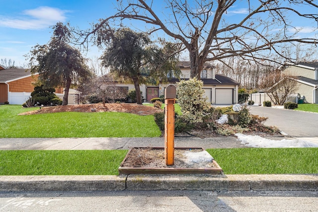 view of front of home with driveway, a garage, fence, and a front yard