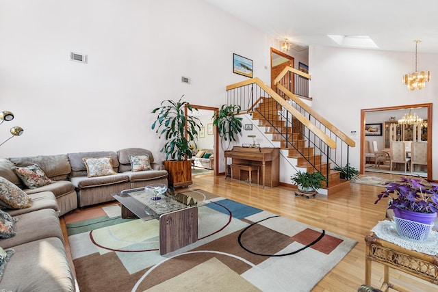 living room featuring a skylight, wood finished floors, visible vents, stairs, and an inviting chandelier