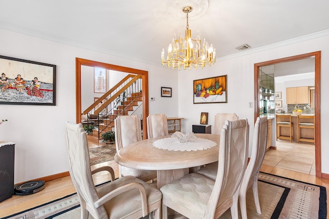 dining space featuring ornamental molding, light wood-type flooring, and stairs