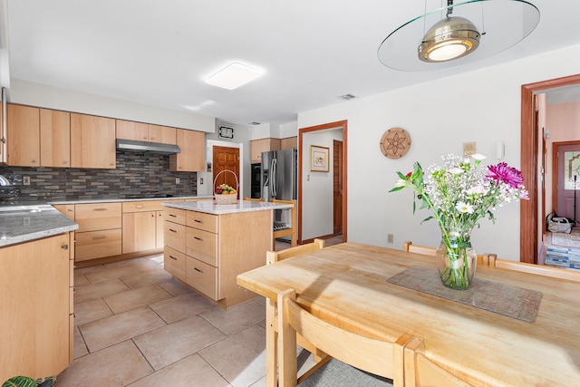 kitchen featuring visible vents, under cabinet range hood, light brown cabinets, stainless steel refrigerator with ice dispenser, and backsplash