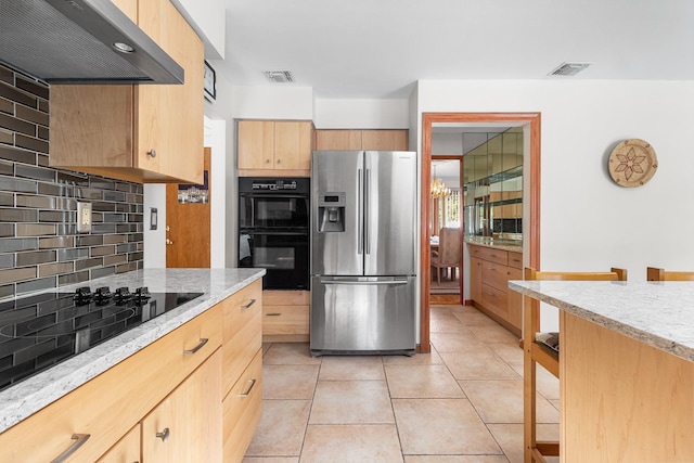 kitchen with black appliances, decorative backsplash, visible vents, and under cabinet range hood