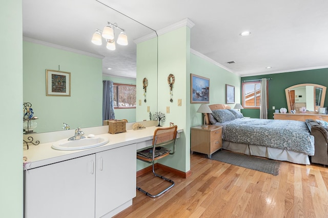 bedroom featuring light wood finished floors, baseboards, ornamental molding, and a sink