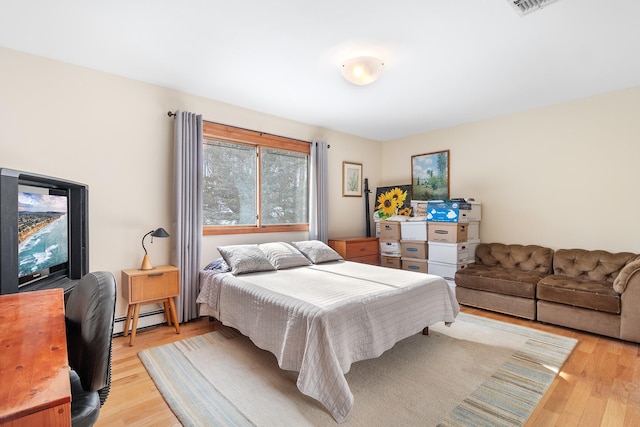 bedroom featuring a baseboard heating unit and light wood-type flooring