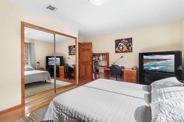 bedroom featuring a closet, wood finished floors, visible vents, and baseboards